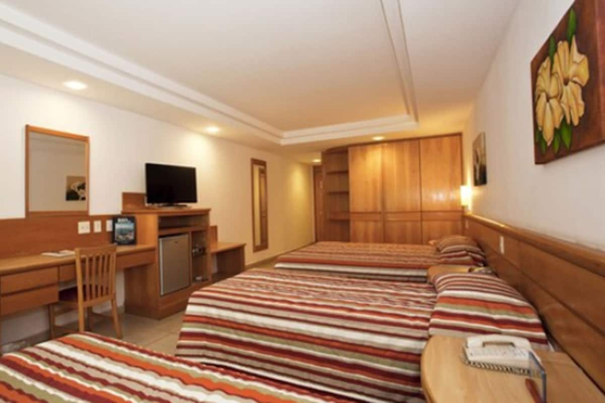Een hotelkamer met een bed, een bureau, een televisie en een kledingkast.