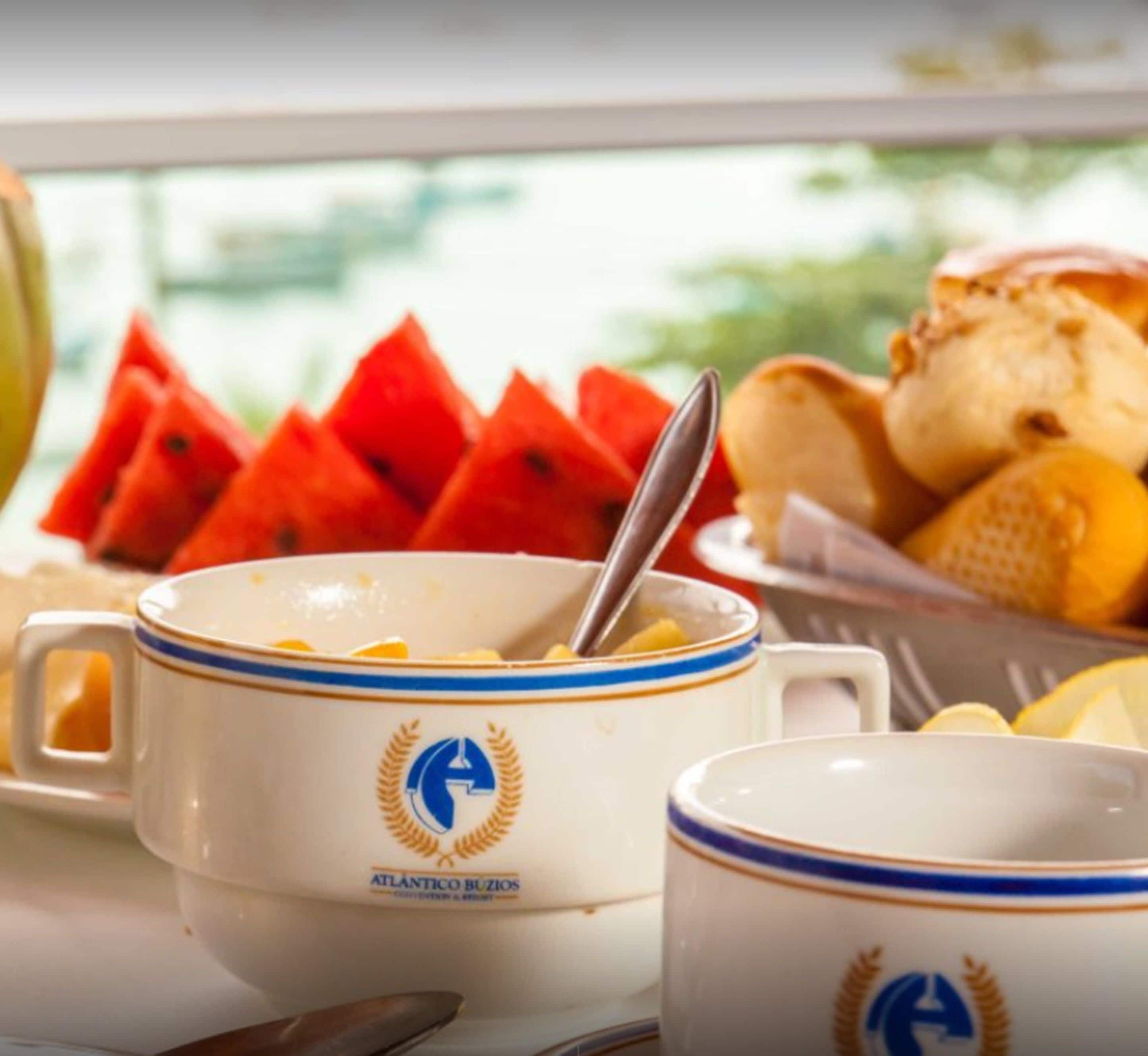 A breakfast setting with a bowl of cereal, a spoon, and a plate of watermelon slices.
