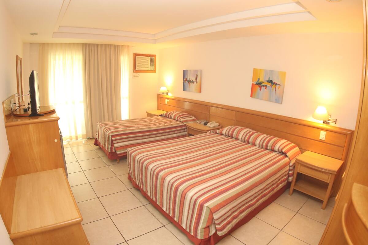 Een hotelkamer met twee bedden, een bureau en een televisie.