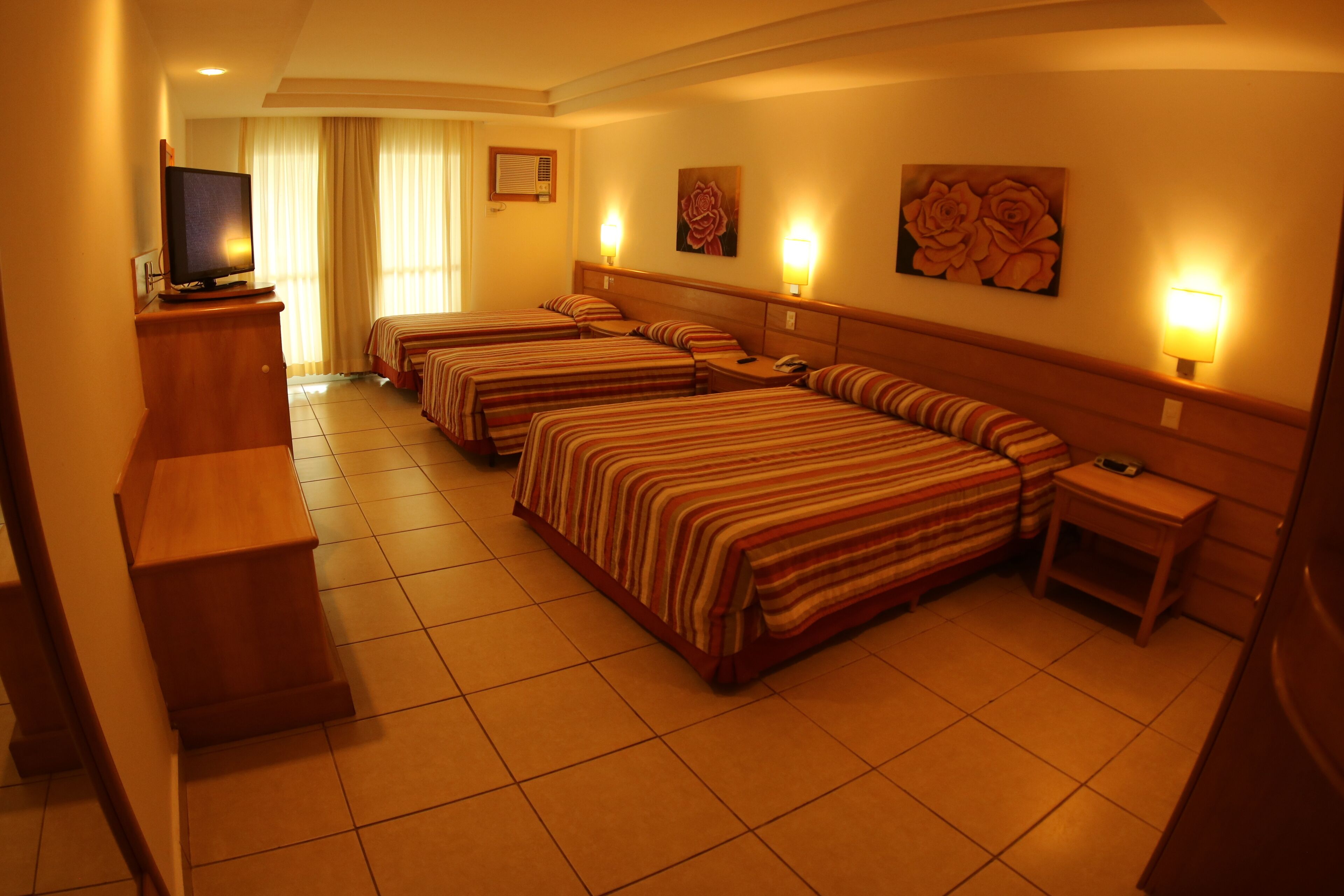 Habitación de hotel con cuatro camas, un televisor y un escritorio.