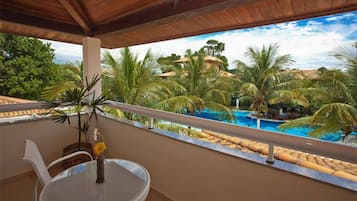 Un balcon avec vue sur une piscine et des palmiers.