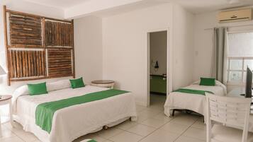 A hotel room with two beds, a small round table, a chair, and a wooden headboard.