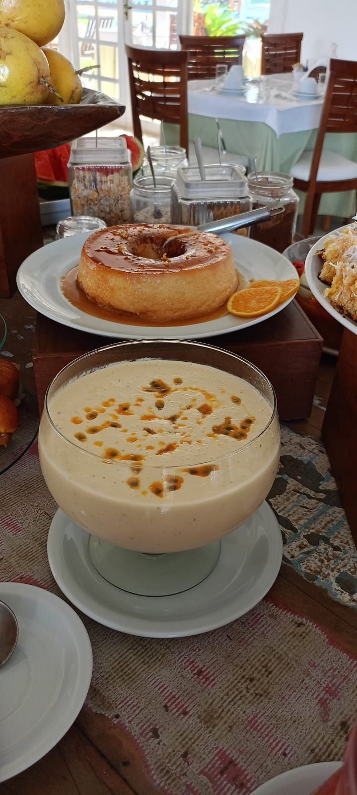 Una mesa de comedor con un plato de postre, un bol de sopa y un cuenco de frutas.