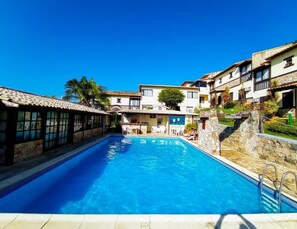Una piscina al aire libre, sillones reclinables de piscina