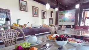 Un bufé de desayuno con diversas frutas, pasteles y un cuadro grande en la pared.