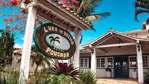 A sign for the Lujar de Ruiz Hotel Pousada with a palm tree and flowers. - Pousada Luar de Buzios (Búzios)
