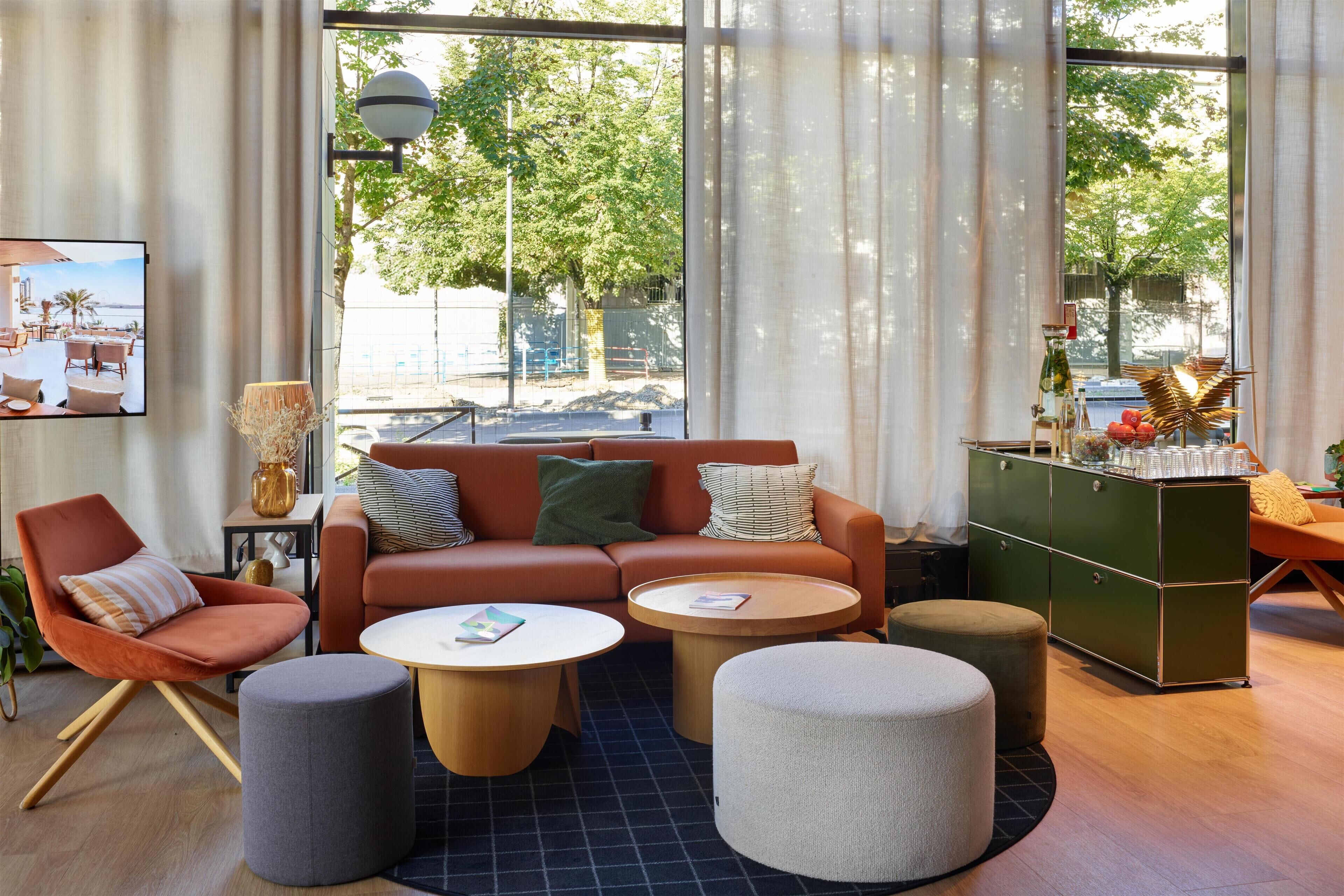 A modern living room with a sofa, armchairs, ottomans, and a coffee table.