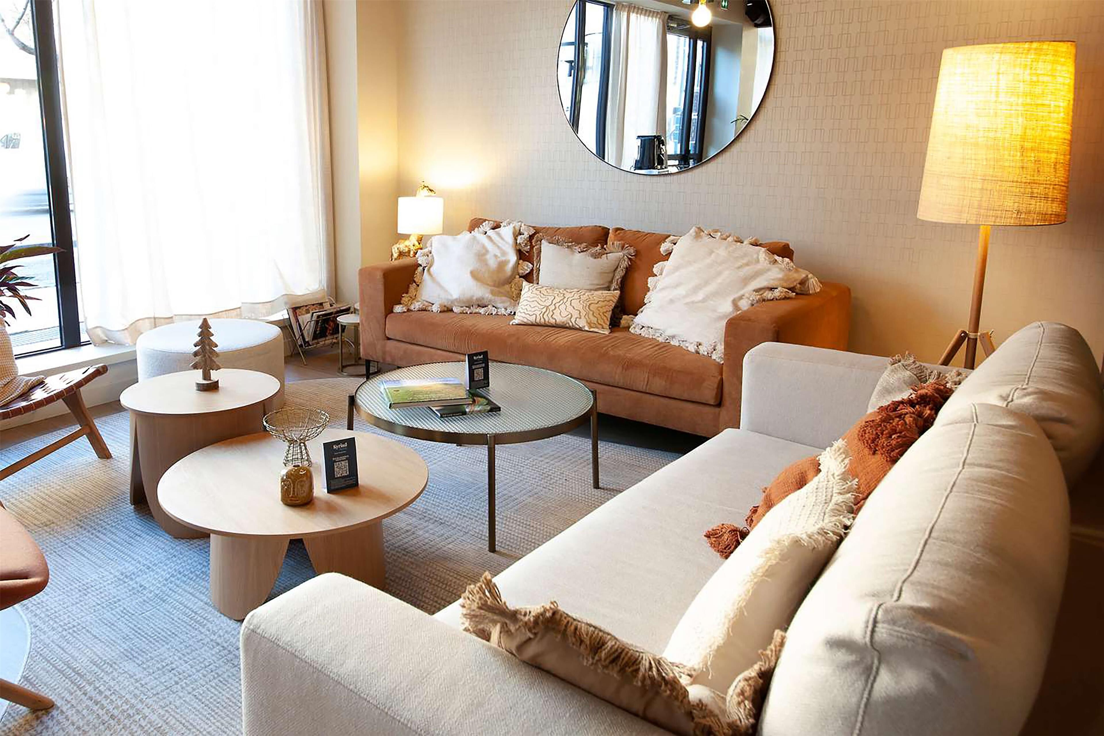 Ein gemütliches Wohnzimmer mit einer Couch, Sesseln, einem Couchtisch und einer Lampe.