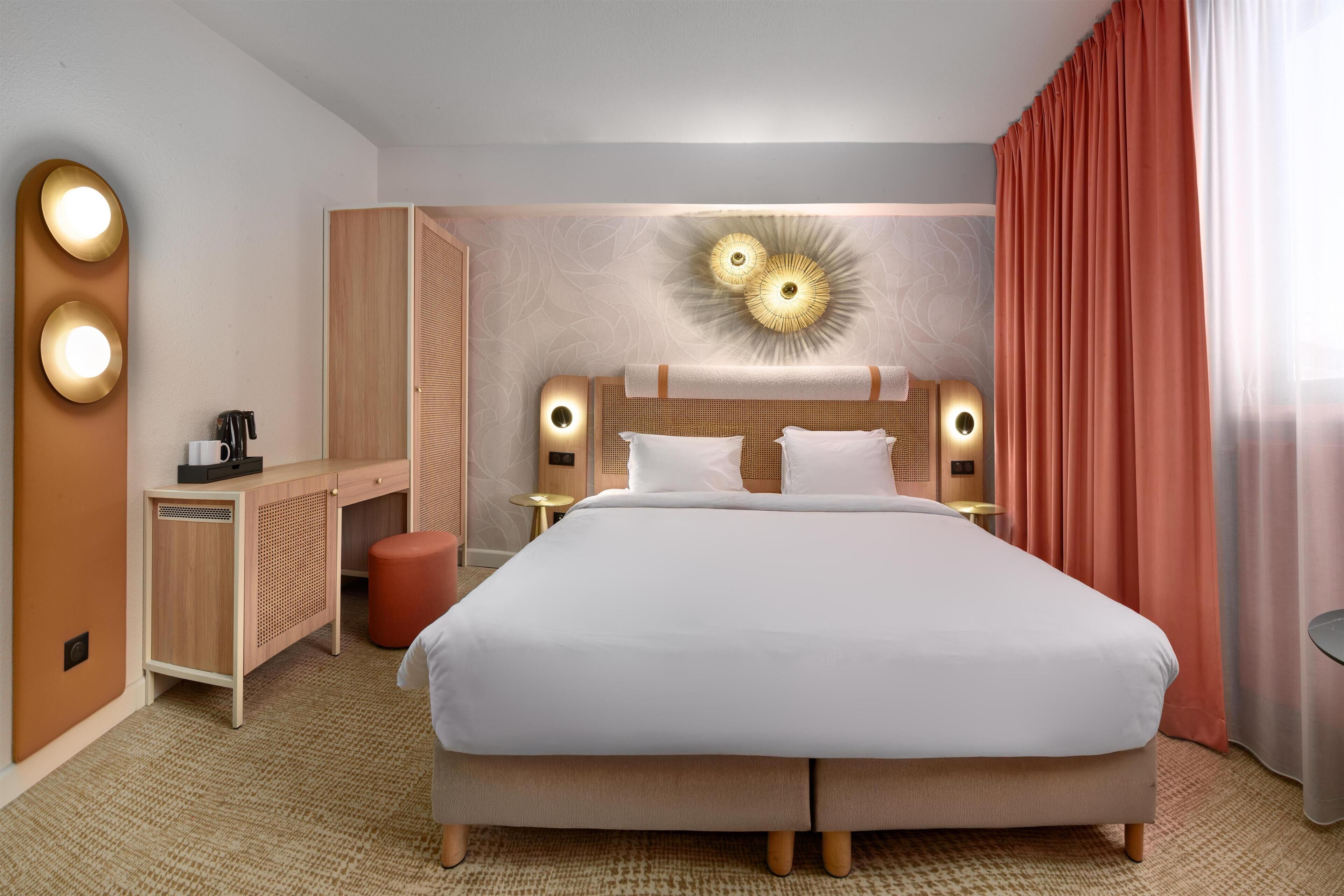 Een hotelkamer met een groot bed, een bureau, een stoel en een klein tafeltje.
