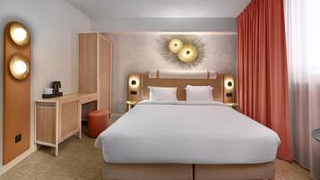 Een hotelkamer met een groot bed, een bureau, een stoel en een klein tafeltje.