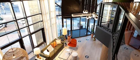 A spacious, modern interior with large windows, a green sofa, a coffee table, and a red chair.