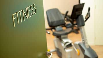 Een deur met de tekst 'FITNESS' die leidt naar een ruimte met fitnessapparatuur.