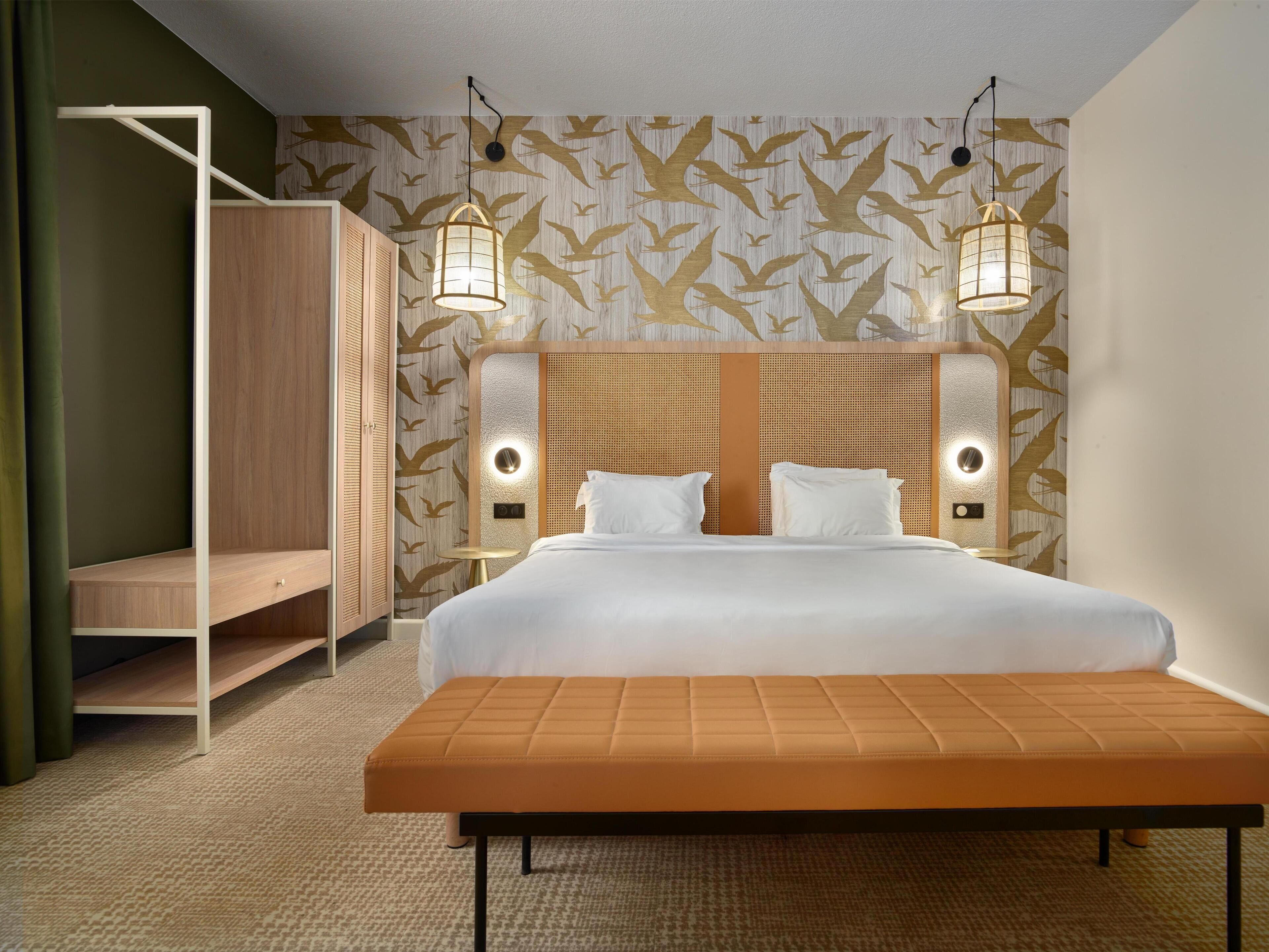 Habitación de hotel moderna con una cama grande, dos mesitas de noche, un armario de madera y un diseño de pared único.
