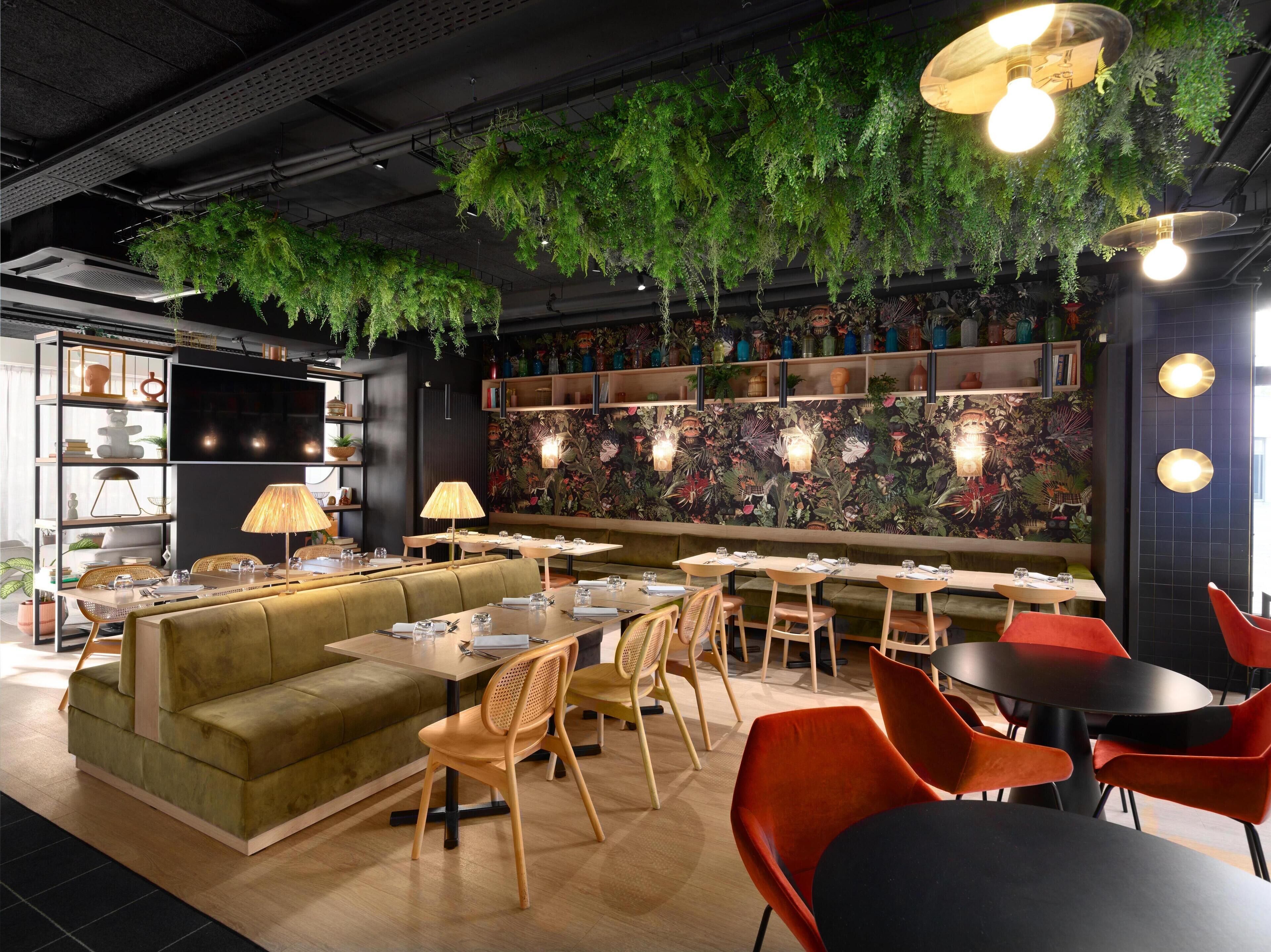 Un restaurant avec un canapé vert, des chaises en bois et des tables.