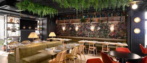 A restaurant with a green sofa, wooden chairs, and tables.