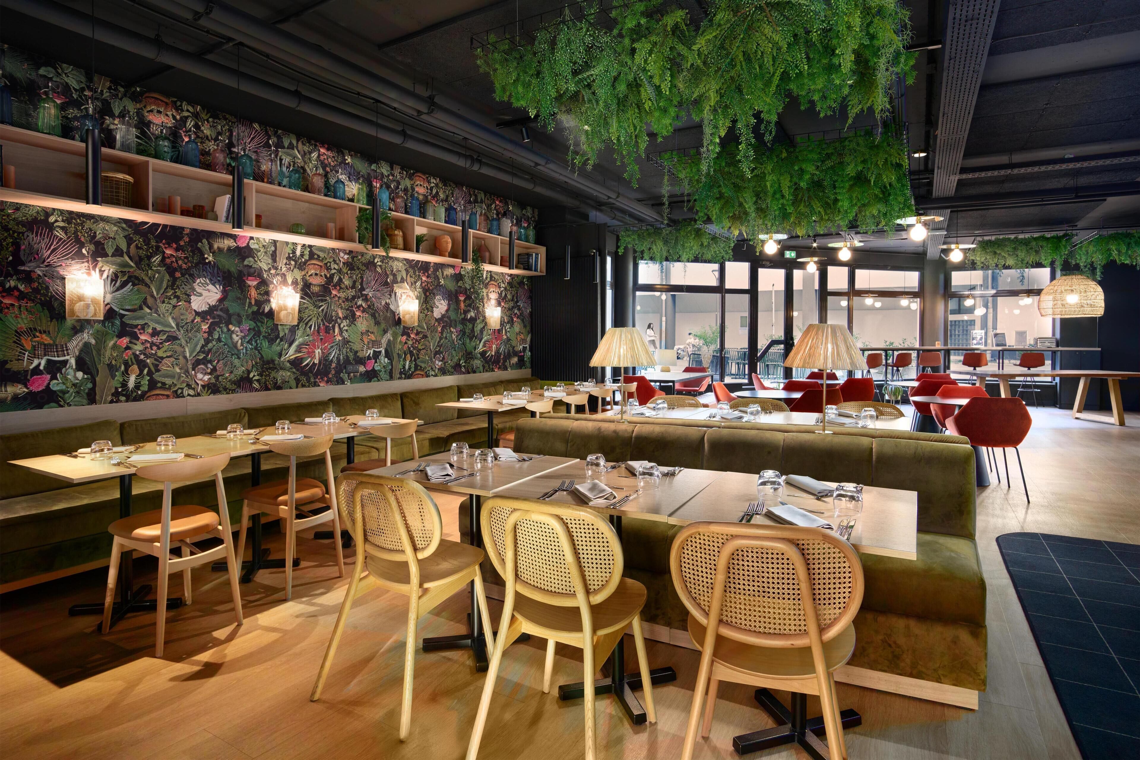 A restaurant with a green cushioned bench seating area, wooden tables, and chairs.