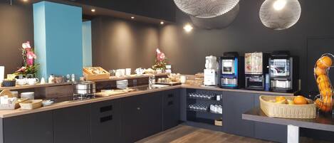 Una barra de desayuno moderna con máquinas de café, una cesta de fruta y un jarrón decorativo.