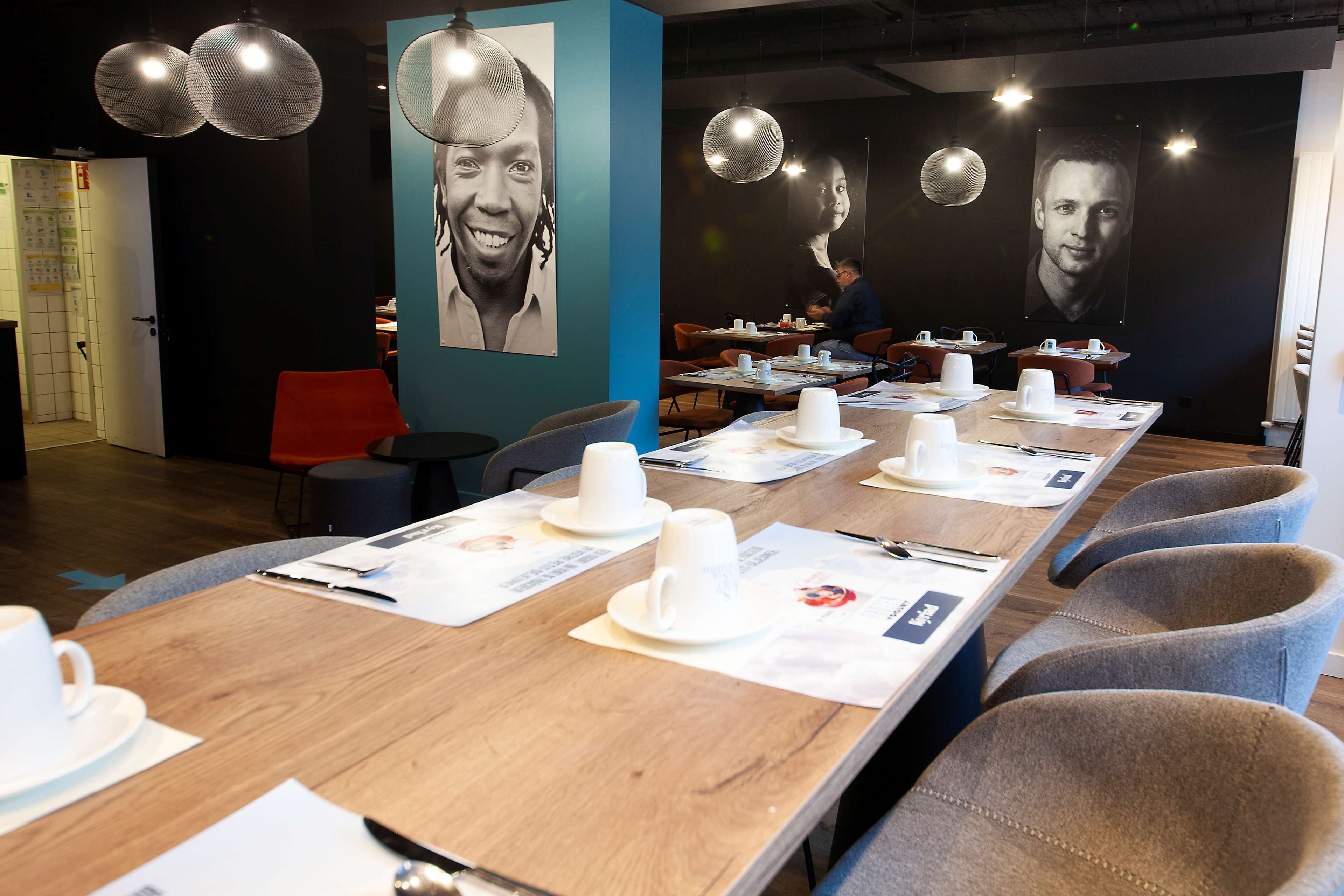 A conference room with long tables, chairs, and white cups on placemats.