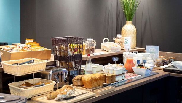 Un bufé de desayuno con diversos alimentos, cestas y una botella de jugo.