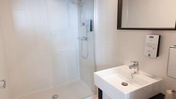 A modern bathroom with a glass-enclosed shower, a white sink, and a mirror above the sink.