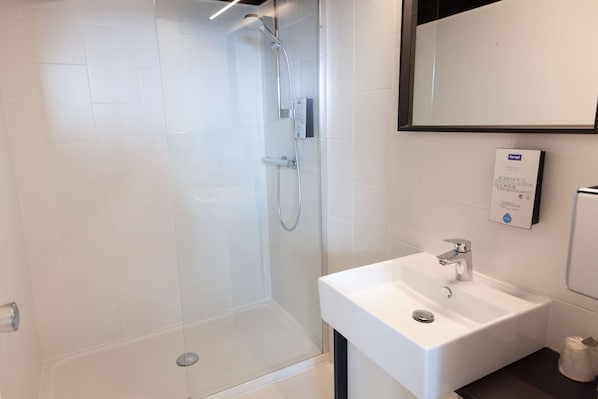 A modern bathroom with a glass-enclosed shower, a white sink, and a mirror above the sink. - Kyriad Clermont-Ferrand Centre (Clermont-Ferrand)