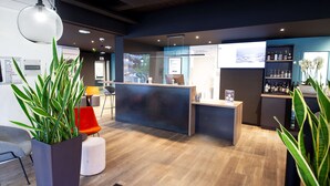 Zona de recepción de diseño moderno, con mostrador de recepción, área de descanso y exhibición de bebidas embotelladas.