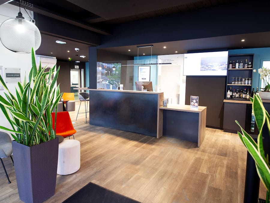 Zona de recepción de diseño moderno, con mostrador de recepción, área de descanso y exhibición de bebidas embotelladas.