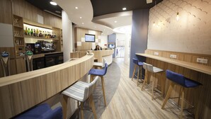 Un espace bar moderne avec des comptoirs en bois, des tabourets de bar bleus et une machine à café.