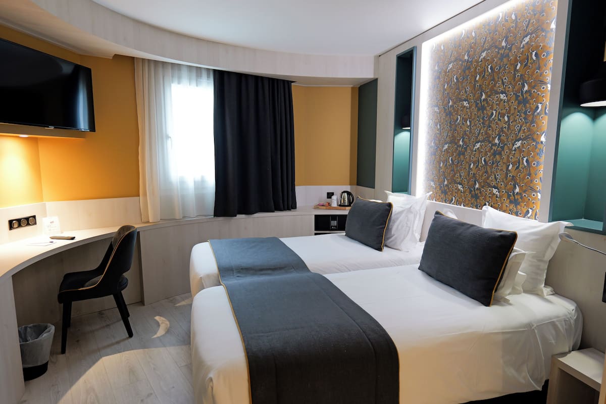 Une chambre d’hôtel avec un lit, un bureau, une chaise et un téléviseur.