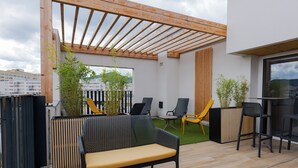 Une terrasse extérieure dotée d’une pergola en bois, d’un espace salon et de plantes en pot.
