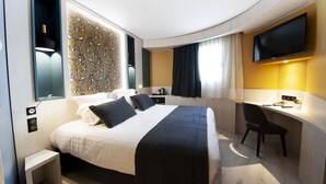 Une chambre d’hôtel moderne équipée d’un grand lit, d’un bureau et d’un téléviseur à écran plat.