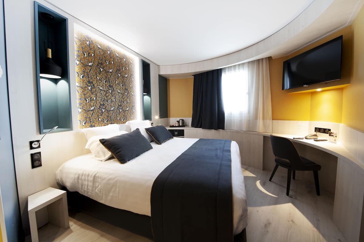 Une chambre d’hôtel moderne équipée d’un grand lit, d’un bureau et d’un téléviseur à écran plat.