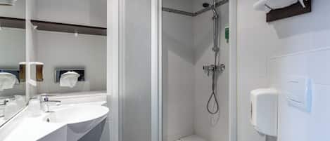 Un baño moderno con ducha envuelta en vidrio, un lavamanos blanco y un inodoro.