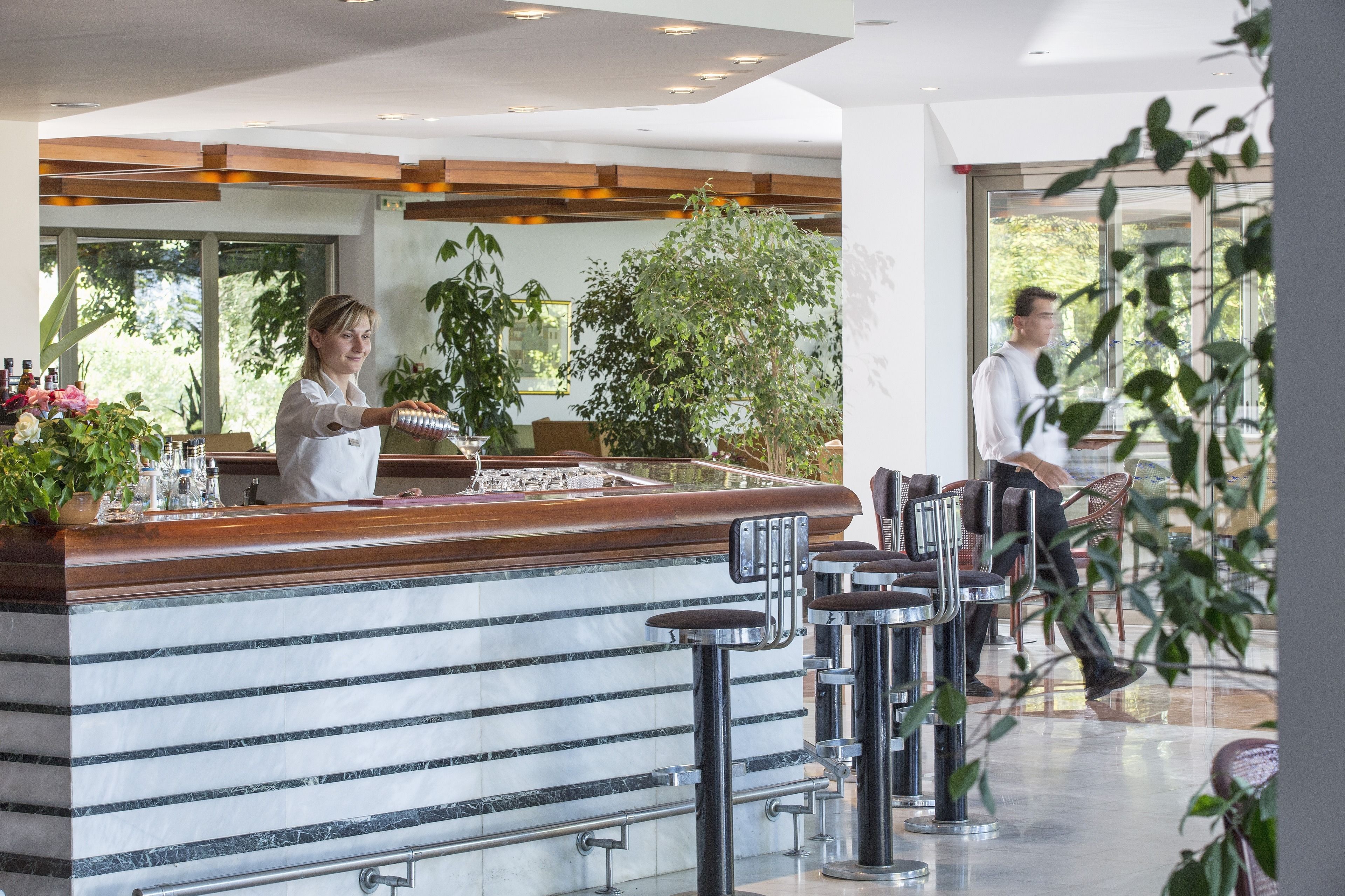 A bar area with a counter, bar stools, and a person serving drinks.