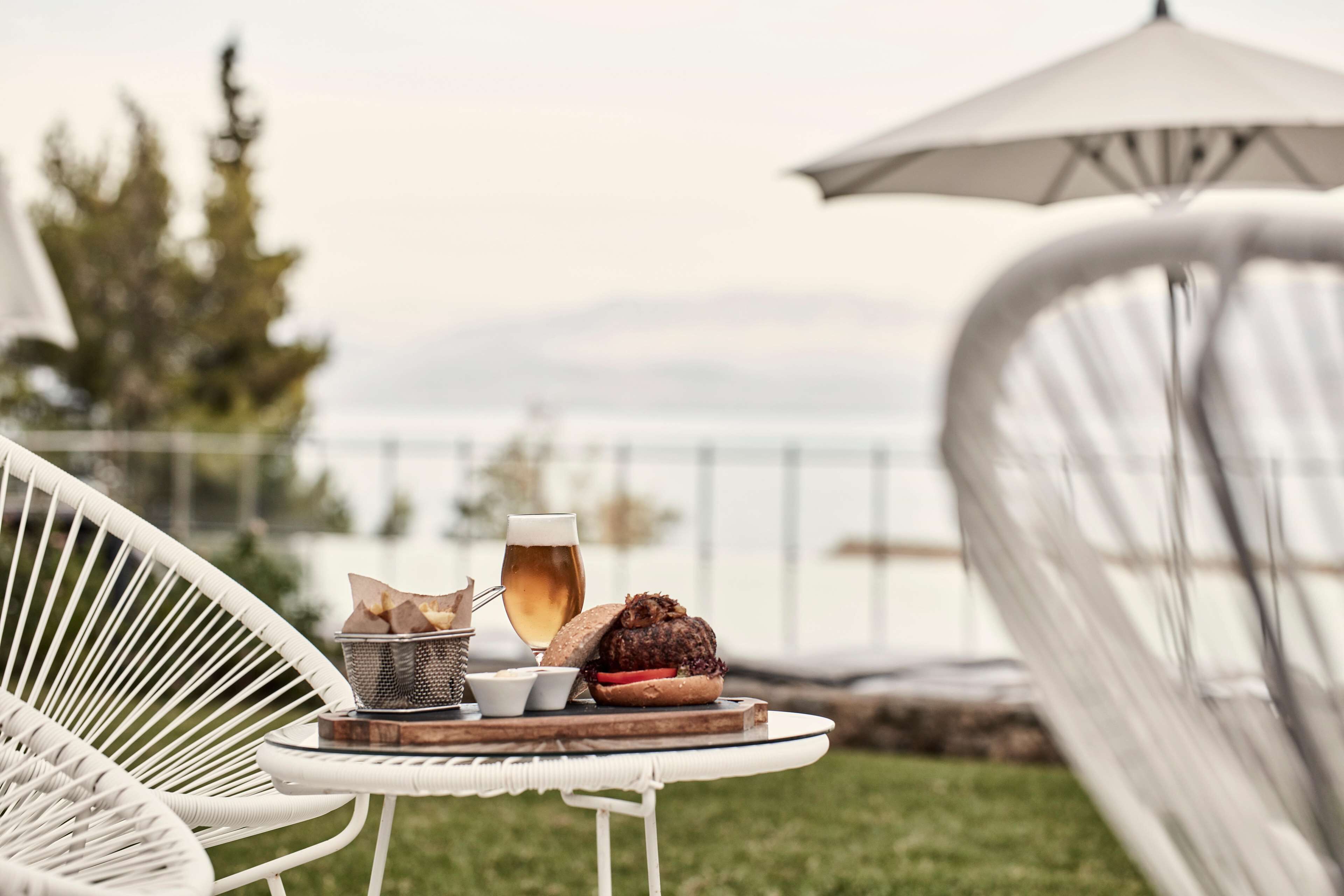 Ein Esstisch mit Mahlzeit, Getränk und Brotkorb, draußen mit Blick auf das Meer.