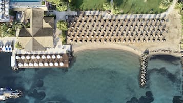 An aerial view of a resort with a beach area, a pool, and a dining area with umbrellas.