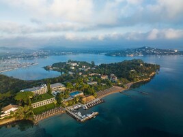 Vista aérea de un complejo turístico costero con varias edificaciones, un puerto deportivo y una extensa masa de agua.