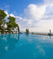 Una piscina con agua azul cristalina, rodeada de árboles y una valla.