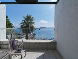 Un balcón con vista al mar, una palmera y una silla.