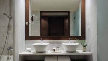 A modern bathroom with two sinks, a large mirror, and a shower.