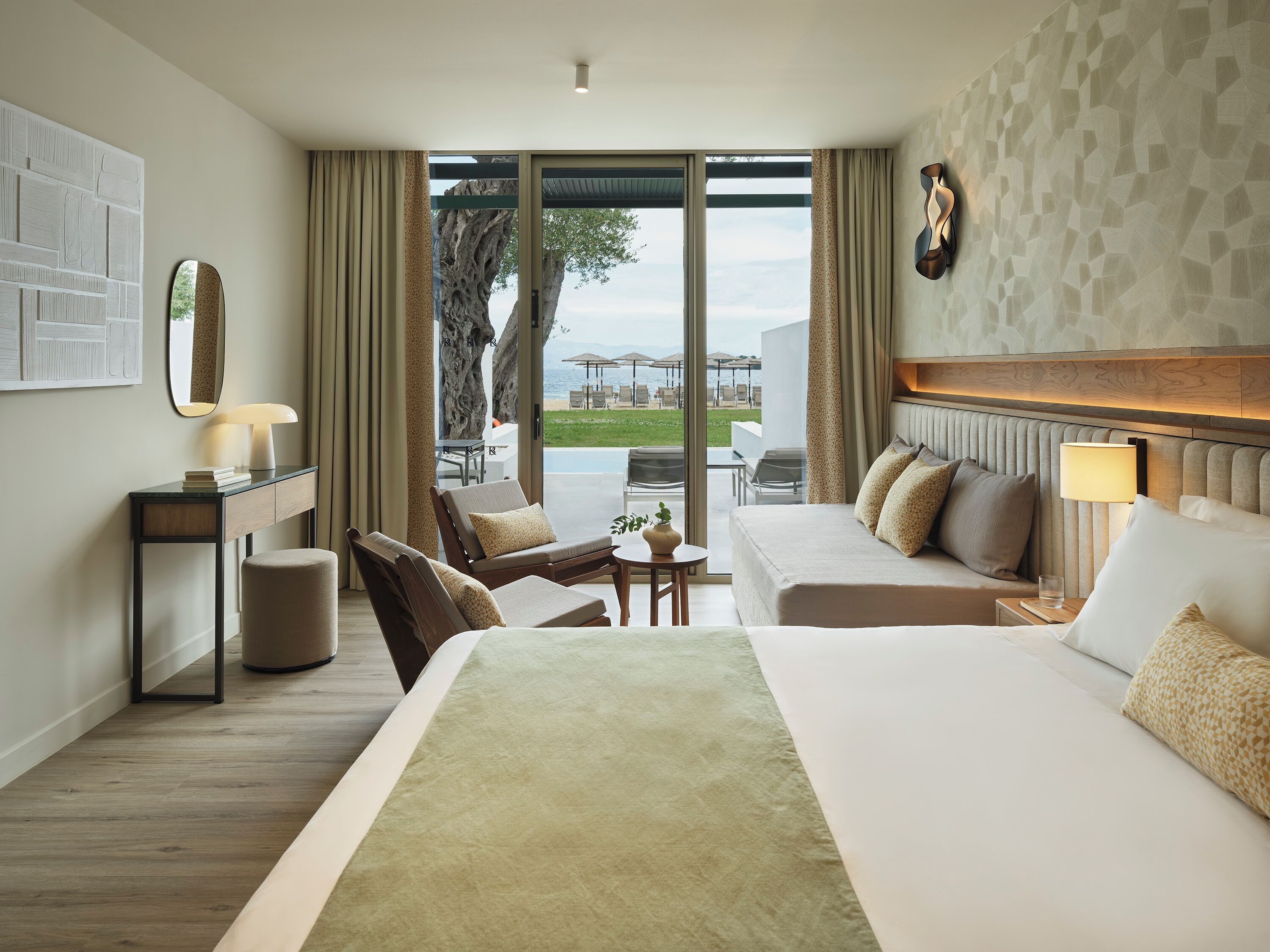 Habitación de hotel con una cama grande, un sofá, un escritorio y vistas al exterior.