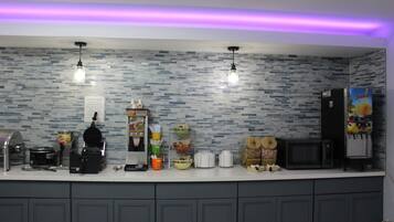 A kitchen with a tiled backsplash, a coffee machine, a microwave, and a refrigerator.