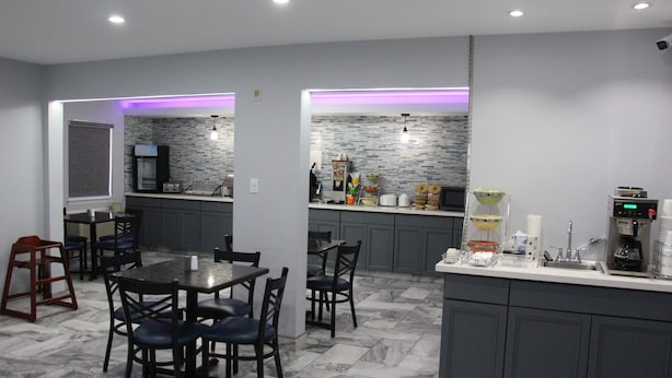 A modern kitchen with grey cabinets, a marble floor, and a central island with a coffee machine. - Douglas Inn And Suites (Cleveland)
