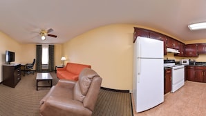 A compact hotel room with a dining area, kitchenette, and a living space with a sofa and armchair. - Douglas Inn And Suites (Cleveland)