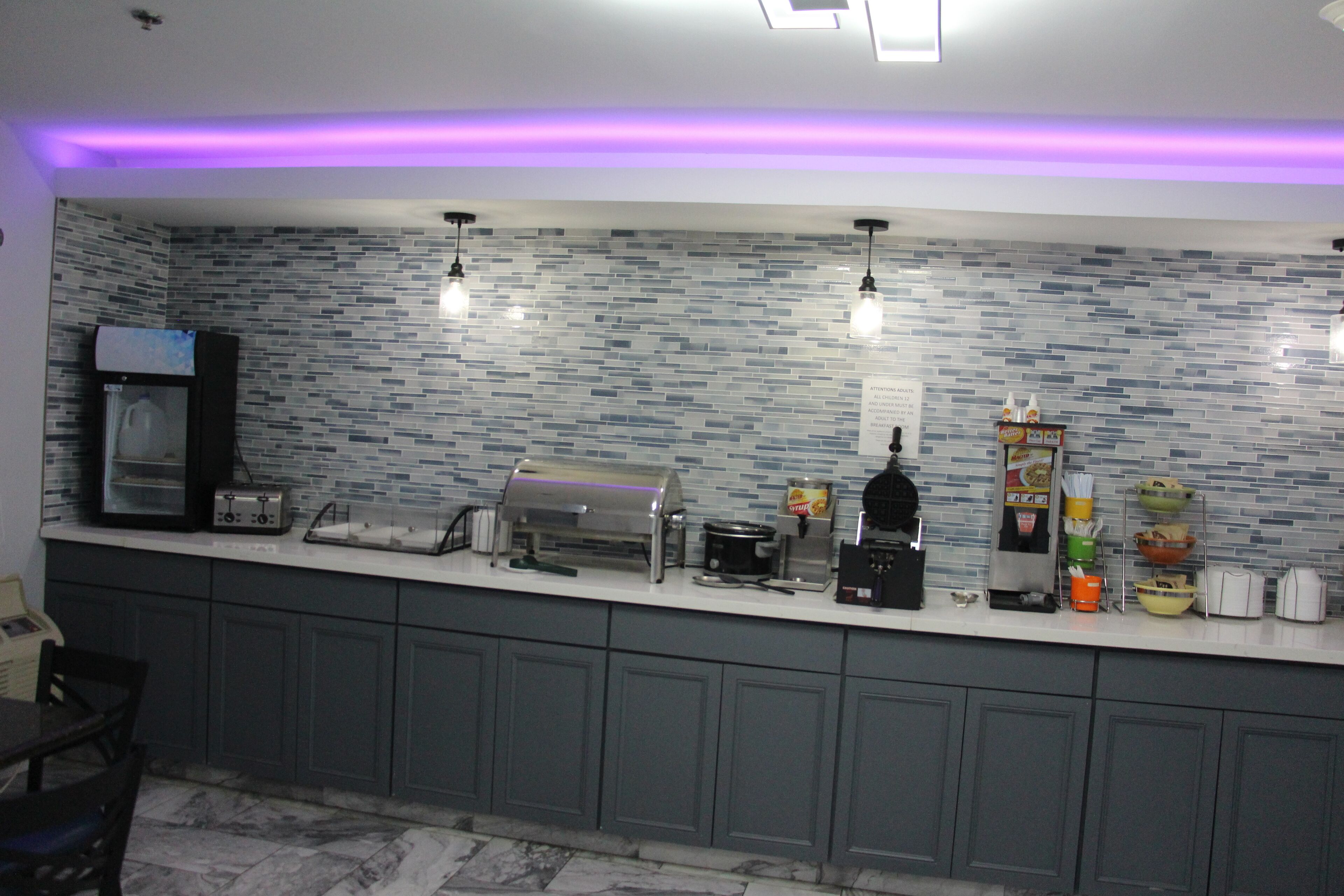 Una cucina moderna con zoccolo a mosaico, elettrodomestici integrati e angolo caffè.