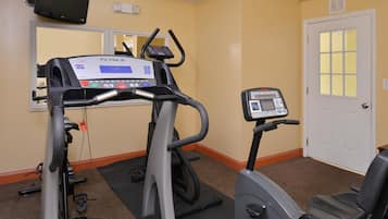 A fitness room with treadmills and an elliptical machine, a door, and a wall-mounted TV.