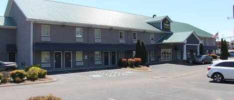 Un motel con estacionamiento, techo verde y un letrero que dice 'Douglas Inn & Suites'.