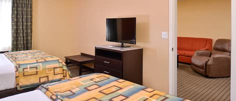 A hotel room with two beds, a TV on a dresser, and a leather chair.
