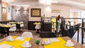 A restaurant with tables set for dining, a stone wall, and a staircase leading to an upper level.