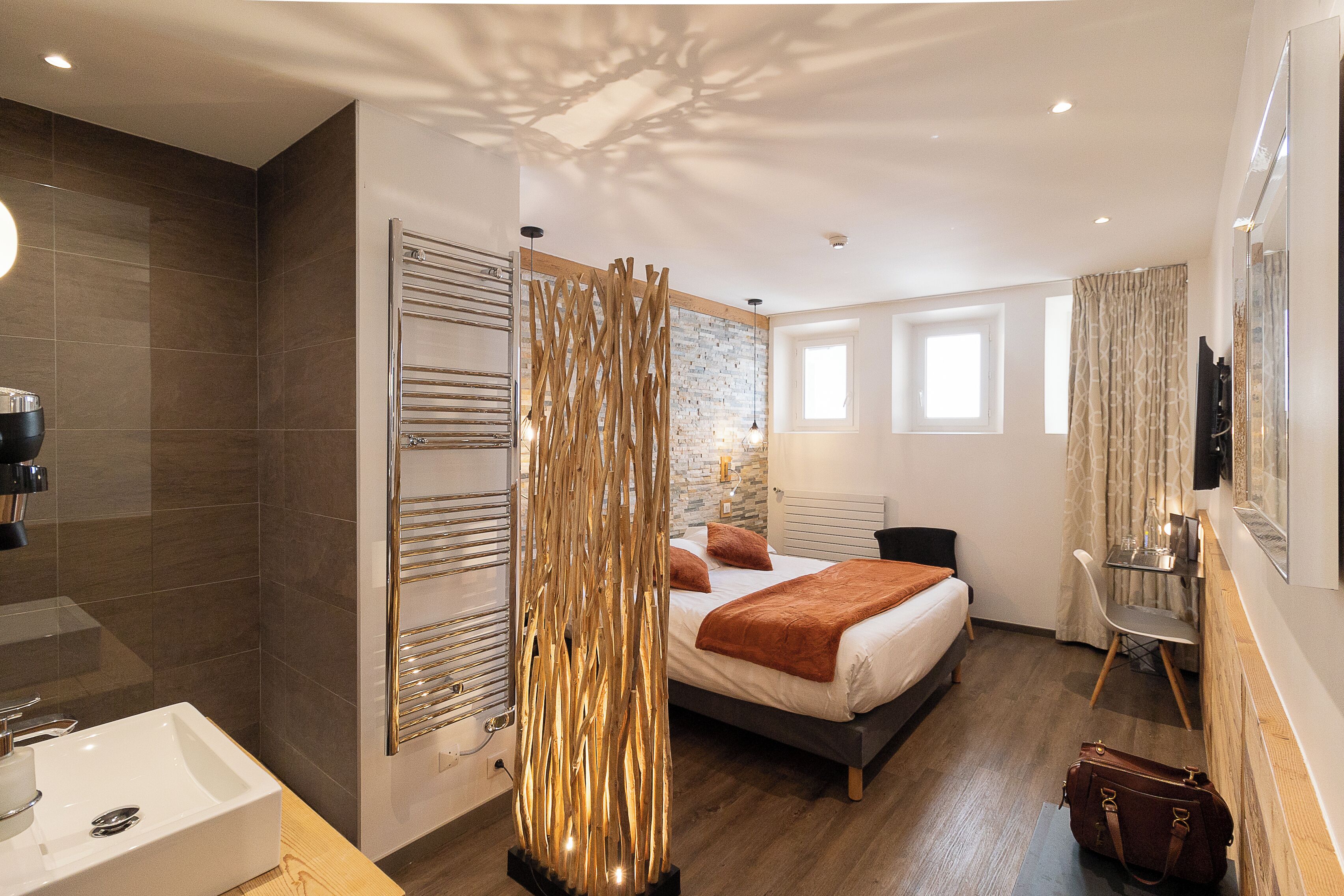 Una habitación de hotel moderna con una cama grande, un baño con lavamanos y un elemento decorativo en la pared.